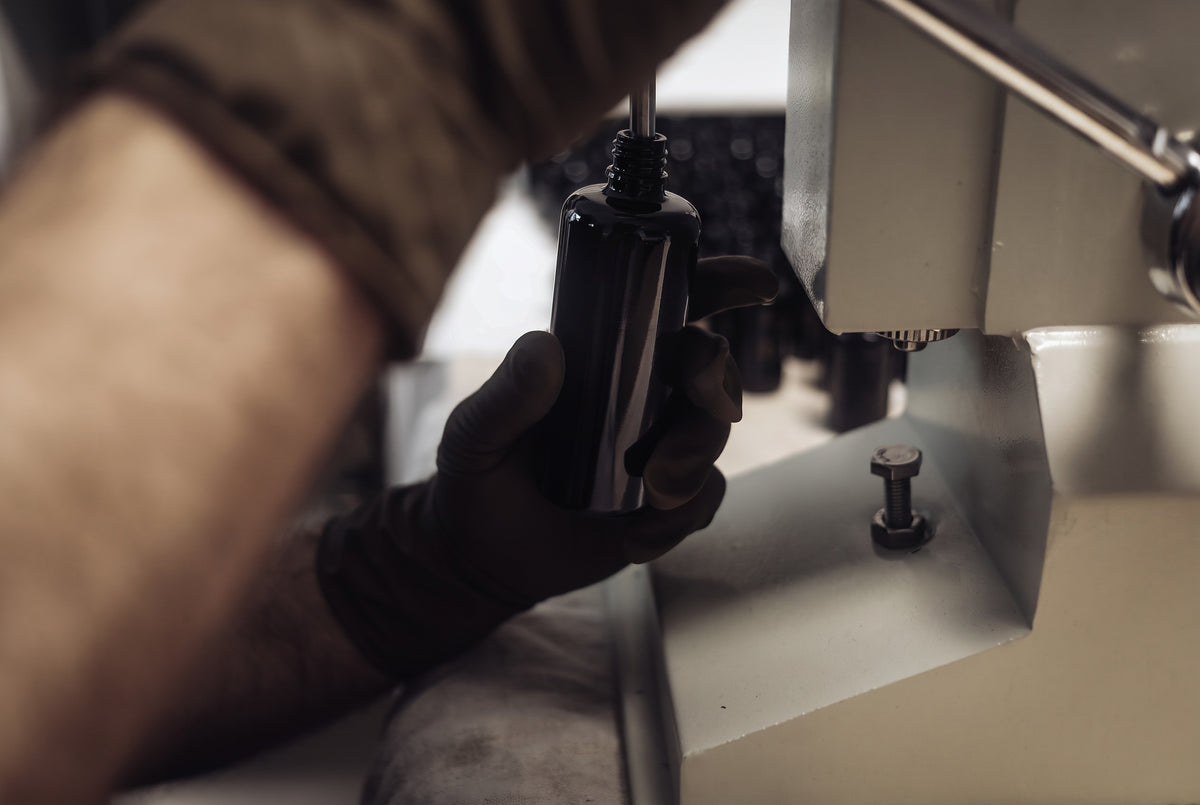 Flasche wird von Hand an der Abfüllmaschine befüllt