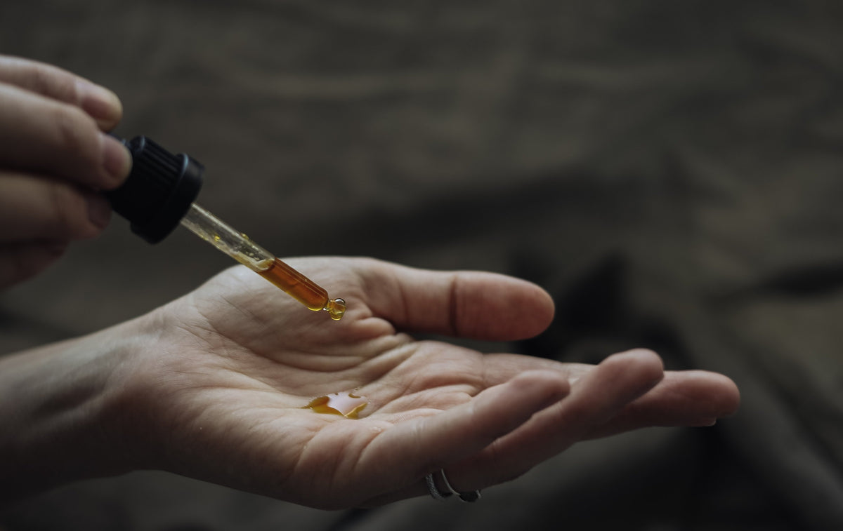pipette dropping golden oil into a palm