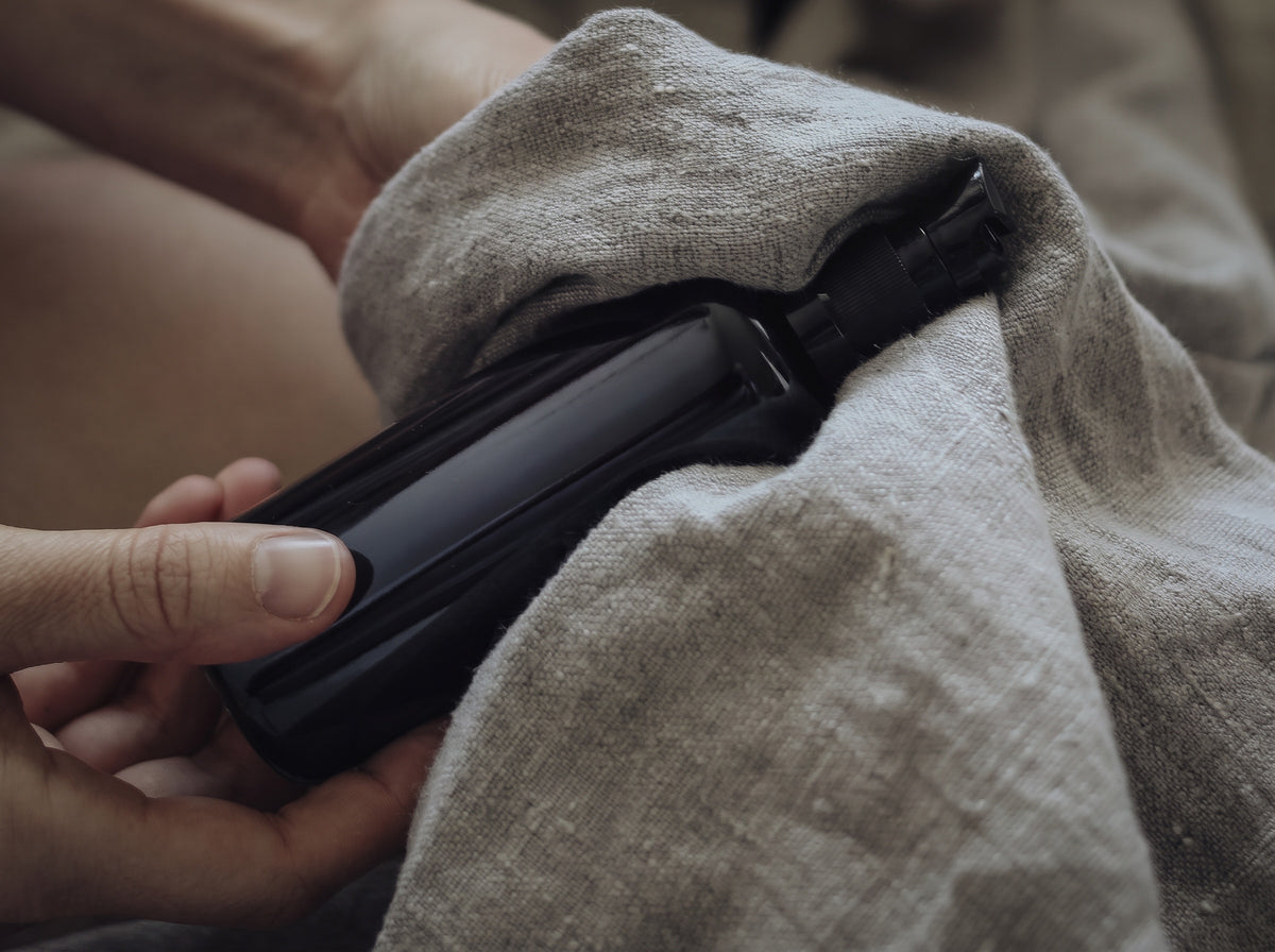 Hand poliert eine schwarze Glasflasche mit Leinentuch