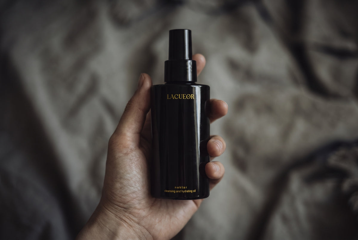 nektar cleansing oil, bottle held in a hand on linen