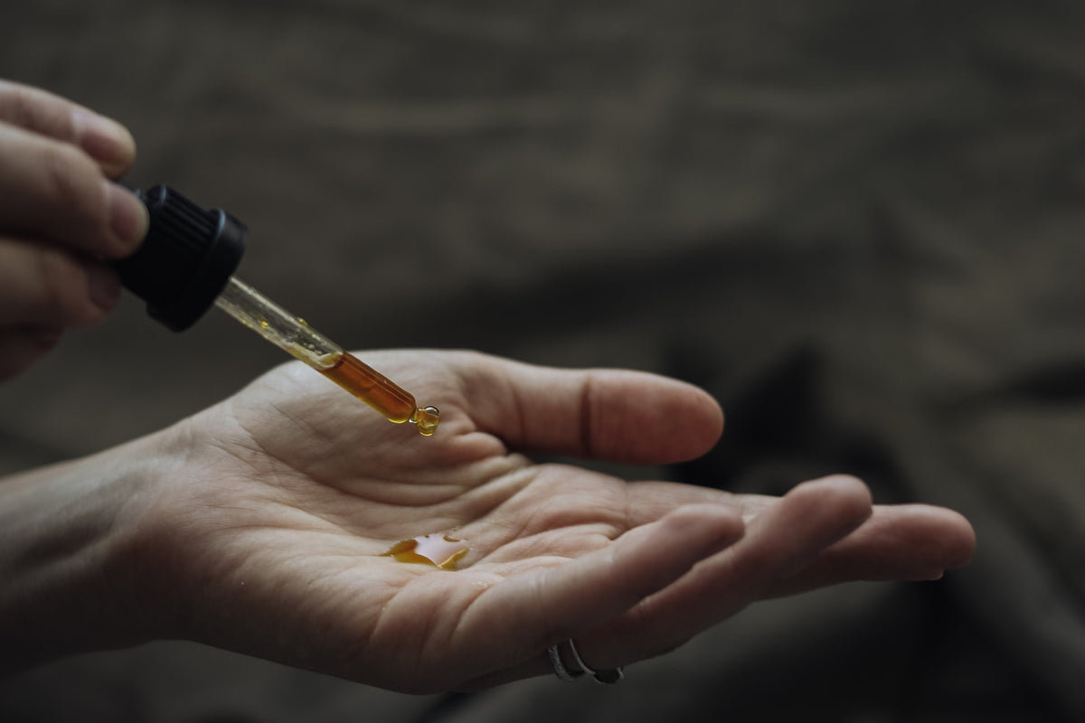 Pipette gibt goldenes Öl in eine Handfläche