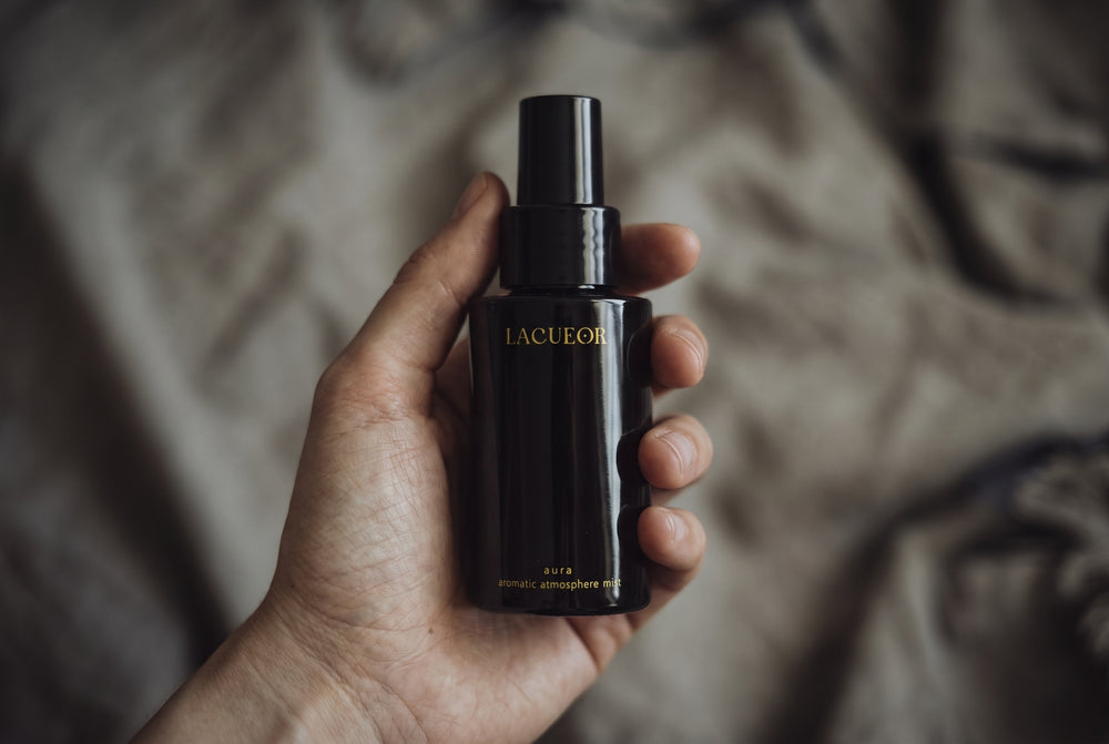 Aura Raumspray, Flasche in der Hand auf Leinen