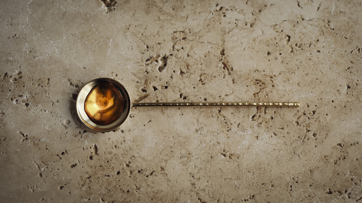 amber gel in a brass ladle on travertine