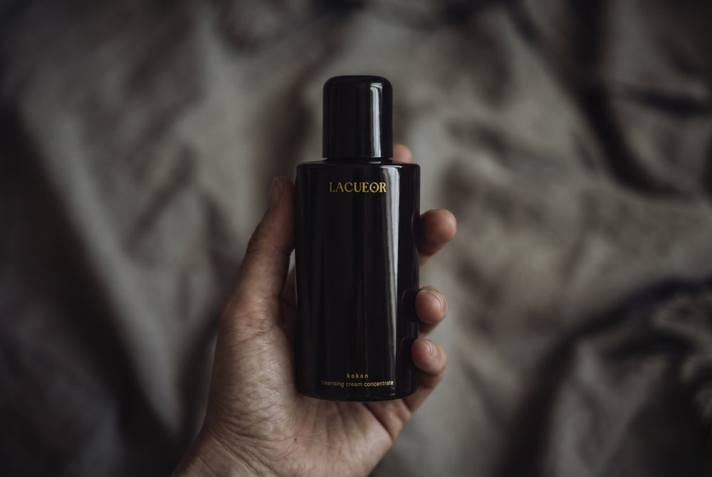 Kokon Reinigungscreme-Konzentrat, Flasche in der Hand auf Leinen