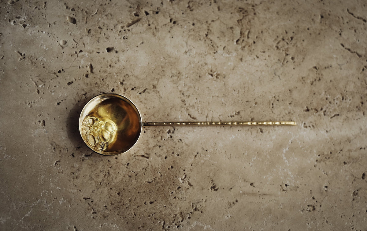 yellow-green nektar oil in a brass spoon