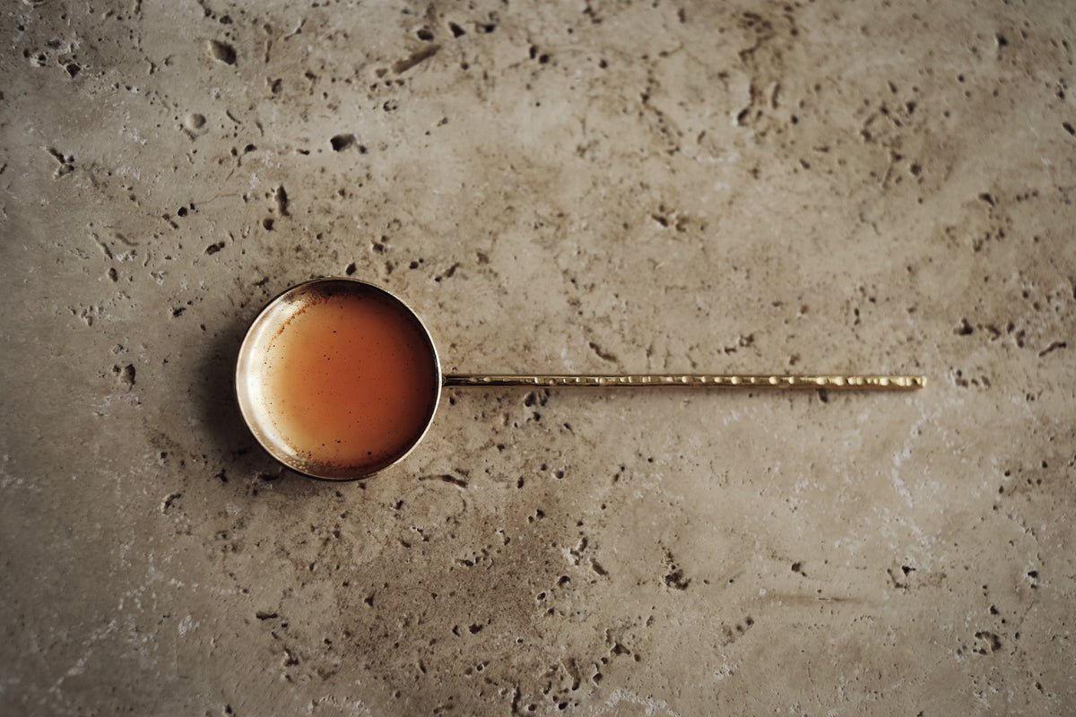peach-coloured tau mist in a brass spoon