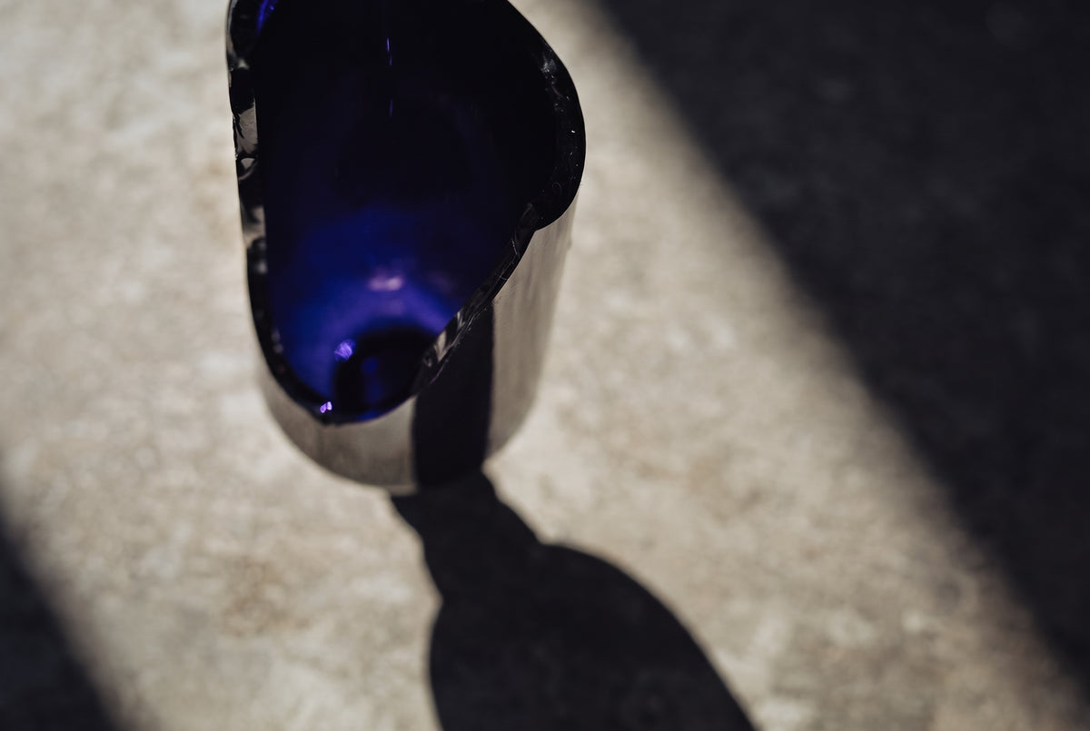 Violettglas-Flasche im Sonnenlicht auf Stein